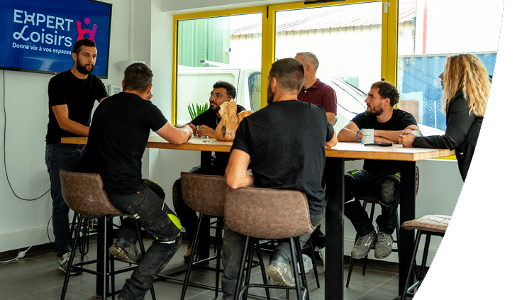 Sept personnes sont assises en réunion autour d'une table. L'équipe d'Expert Loisirs travaille autour de vos projets d'aménagement.