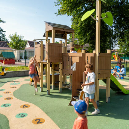 Aire de jeux sur sol en EPDM avec chiffres, jeu à ressort et toboggan vert. Des enfants jouent dans l'aire de jeux