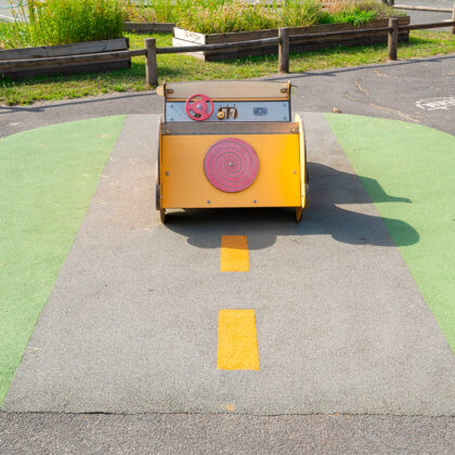 Une petite voiture pour enfant est fixée sur un sol EPDM qui représente une route.
