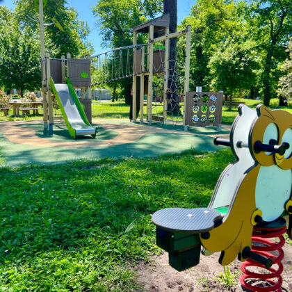 Aire de jeux avec verdure, soleil. Toboggan et toile d'araignée, jeu à bascule enfants hibou