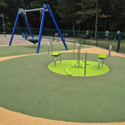 Aire de jeux avec balancelle et tourniquet intégré au sol.