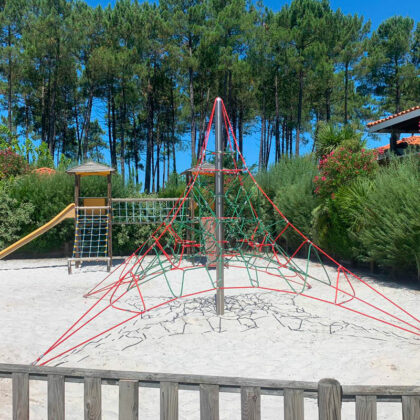 Aire de jeux, toile enfant escalade et toboggan sur sol sable